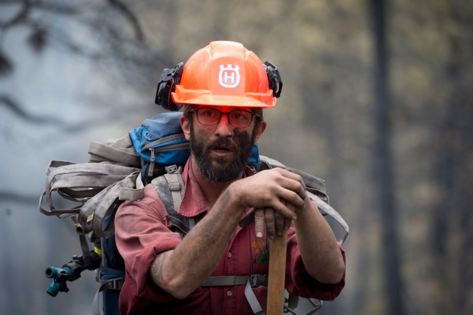 Firefighter Jake Sparks pauses for a moment on Saturday at the Smith Creek fire on a hillside in West Kelowna. More than 2,500 residents of the area were evacuated when the fire suddenly grew.