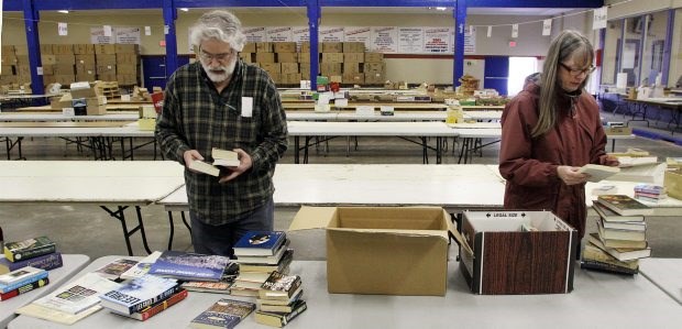 Al Haines (left) and Jane Murtz sort books as volunteers start setting up for the saʴý Book Sale at the Victoria Curling Club.