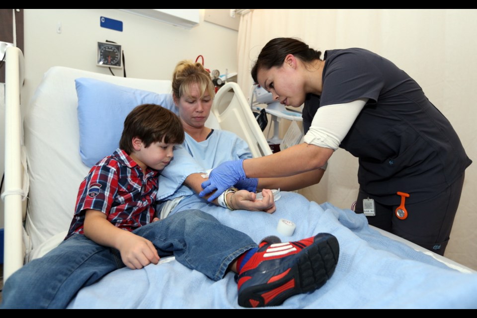 Sabrina Blanchard checks on patient Carmen Maa while Maa's son, Kyle, looks on. Blanchard is a member of the Selkirk First Nation in the Yukon and is the 500th person from a First Nations culture to be hired at Island Health.