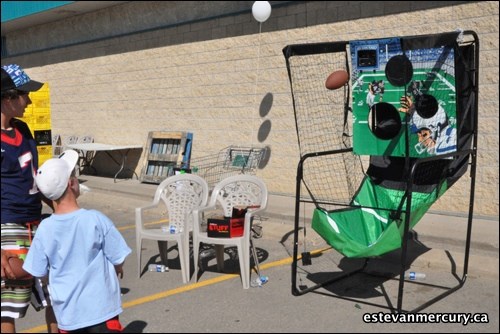 Kendel Spencer gives the football throw a try as an Elecs player watches.