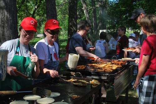 Connie Smith and Grace Rose, members of the Manor Museum Board, cook up pancakes to serve between 250 and 300 people during the Manor Canada Day pancake breakfast. In the background, Joanne Soroka serves up sausages to fill the stomachs of those in attendance.