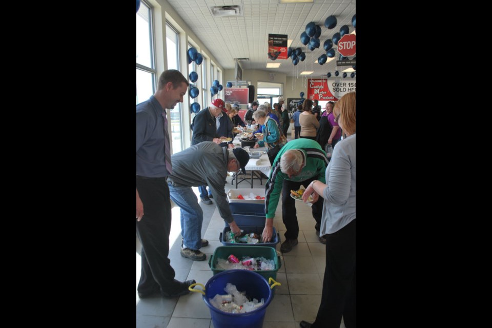 A long line of people take part in the free lunch provided by Carlyle Motor Products for the anniversary celebration. Donations accepted went to the annual Sink or Swim event in Carlyle.