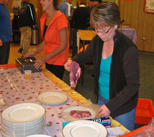 Sharing out the hearty steaks that are part of the traditional Great Pumpkin Weigh-in dinner, Sherri Metz gets plates ready for the assembly.