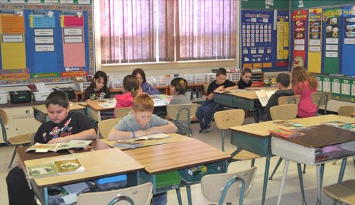 The grade two/three split class quietly concentrates on their books during class.