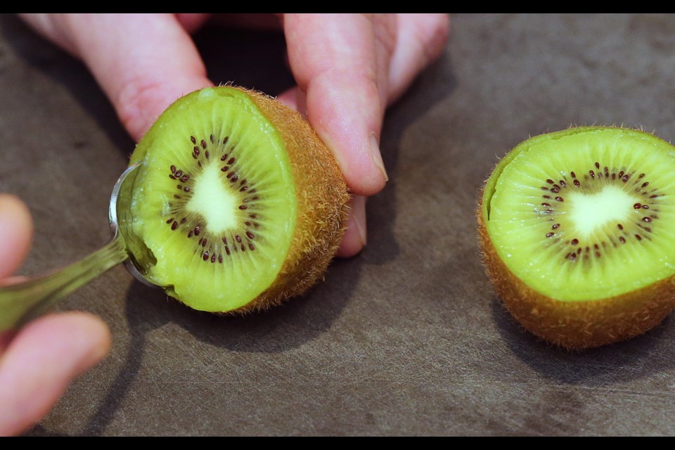 Step 1: Cut the kiwi in half between the stem and blossom ends. Grab one of the half kiwis and gently insert a teaspoon between the skin and the flesh. Work the spoon around the outer edge of the kiwi. Do the same with the other half kiwi.