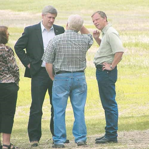 Prime Minister Stephen Harper and Premier Brad Wall speak with producer Ron Blommaert at the latter&#8217;s farm near Yorkton.