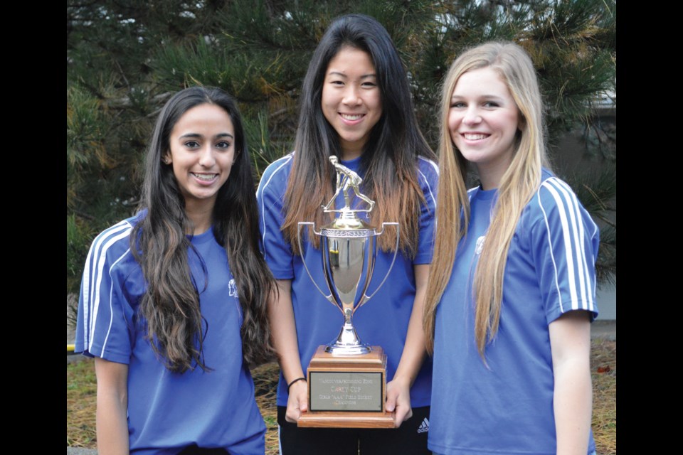 McMath captain Rachel Kwan (middle) and assistants Harmony Sander (left) and Ellie Reid pose with the Carey Cup zone champions trophy, named after longtime Richmond field hockey contributors Lance and Nancy Carey.