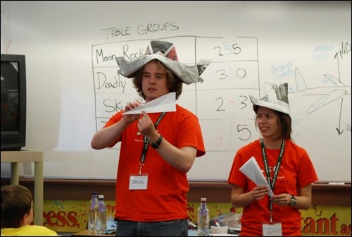 Volunteer instructors Byron Mikituk and Terra Lekach give a lesson in aerodynamics as they demonstrate how to construct the perfect paper airplane.