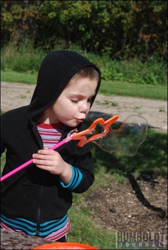 Joshua Schmidt blows a big bubble at the Humboldt and District Community Services booth.