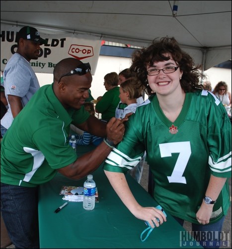 Hugh Charles of the Saskatchewan Roughriders grins as he signs the jersey of very happy Rider fan Jocelyn Ehr (right).