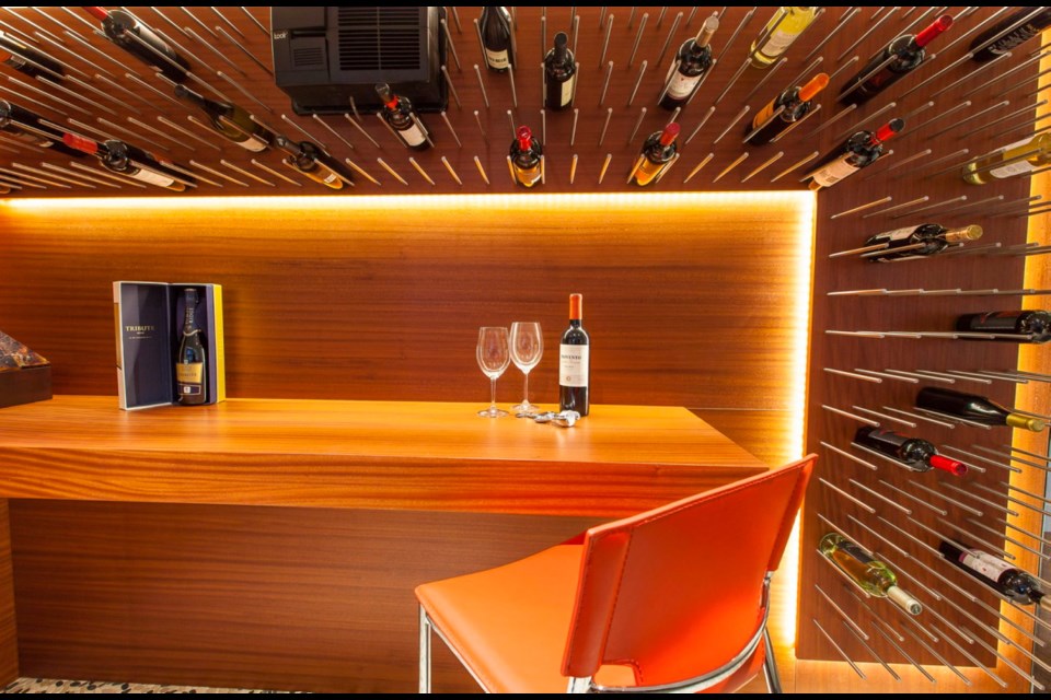 This temperature-controlled wine display area was built along the back of a media room. It makes efficient use of space as the bottles simply slip between metal rods in the vertical wine rack.