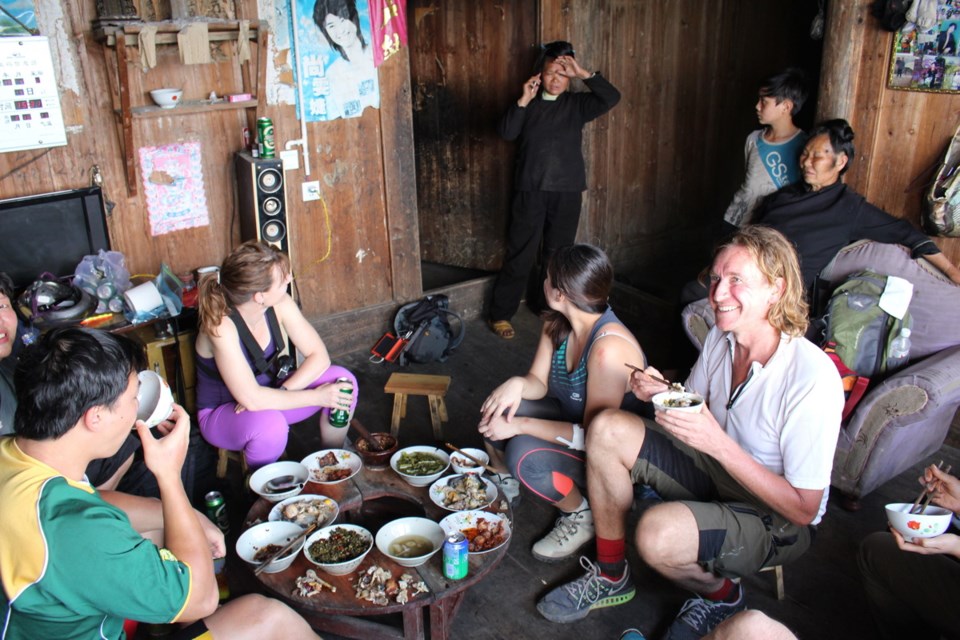 Bruce Foreman, right, enjoys a home-cooked meal hosted by a Miao family in Kong Ming village, near Rongjiang in Guizhou province, China. Foreman runs a Hong Kong-based tour company called Bikeaways. The Miao, who are related to the Hmong in other parts of Asia, typically live in fir-framed houses with living quarters on the second floor, animal pens below. Residents of this village say they only received electricity about four years ago, hence the television in the corner.