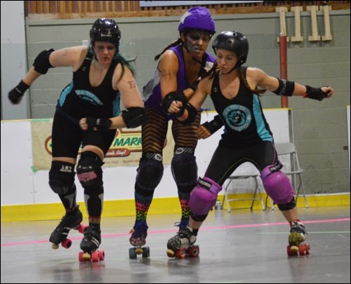 A pair of Sirens sandwich a Betties player during roller derby action on Saturday (May 30).