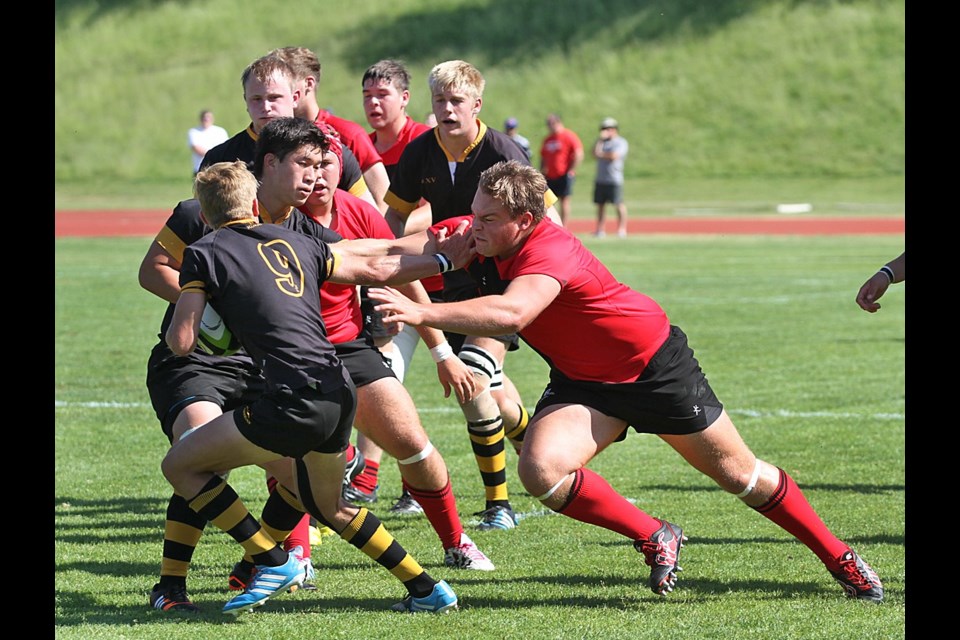 St. George’s Sam Turner, in red, tries to bring down Shawnigan Lake’s Simon Gray in the B.C. AAA senior boys rugby championship at Rotary Stadium in Abbotsford on May 30, 2015. The Shawnigan Lake Stags defeated the Saints 35-5. Photo Jean Konda-Witte