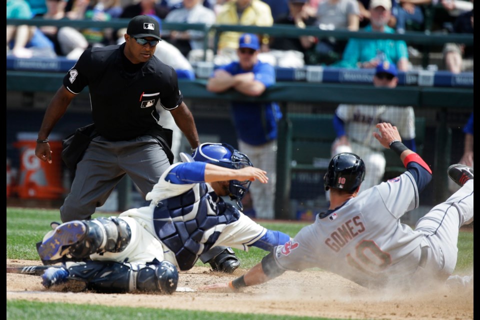 Cleveland Indians' Yan Gomes, right, is out at home on a tag by Seattle Mariners catcher Welington Castillo, as Gomes tried to score on a grounder by Jose Ramirez during the sixth inning of a baseball game, Sunday in Seattle. Home plate umpire Alan Porter watches the play.