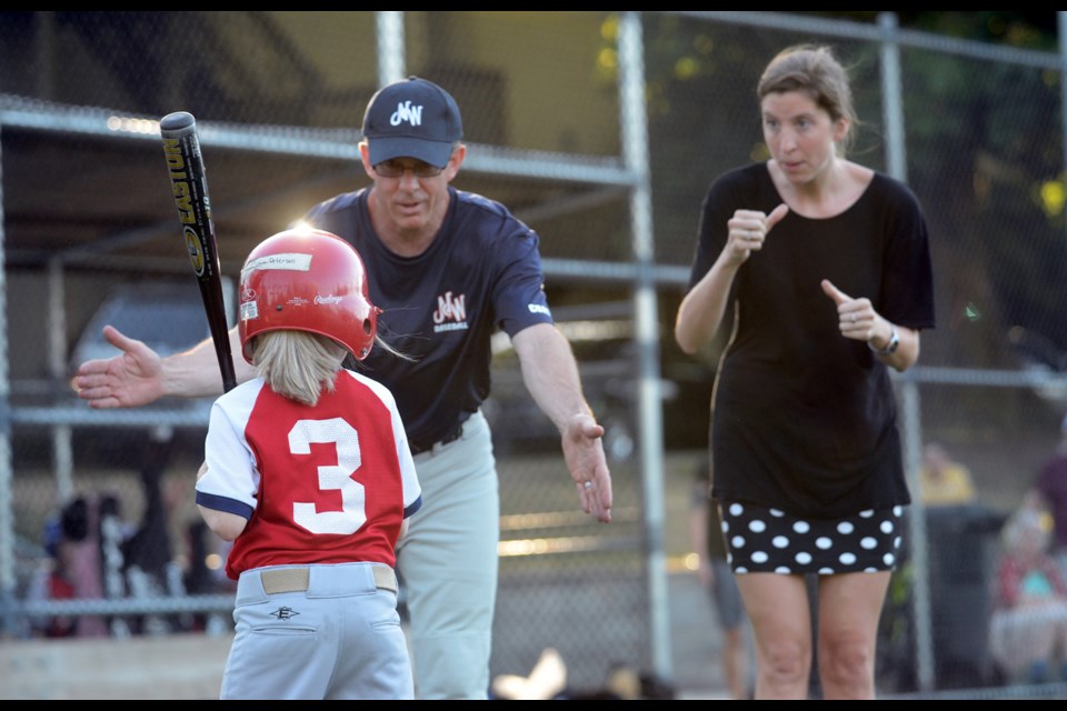 New West Red Cardinals coach Ian Williams gives tips to batter Ciara Peterson with help from sign-language interpreter Brynn McIntosh during a game at Queen's Park last month.