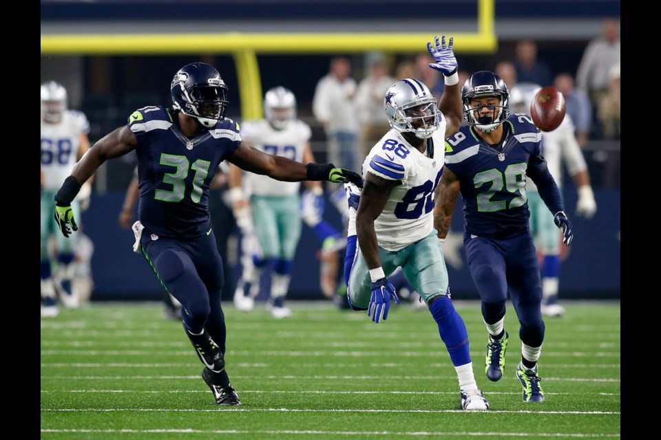 Dallas Cowboys wide receiver Dez Bryant (88) can't reach a deep ball as Seattle Seahawks strong safety Kam Chancellor (31) and Seattle Seahawks' Earl Thomas (29) defend late in the second half on Sunday at AT&T Stadium in Arlington, Texas.