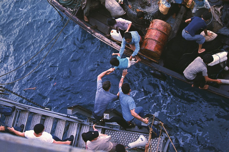 Crewmen of the amphibious cargo ship USS Durham take Vietnamese refugees aboard a small craft in the