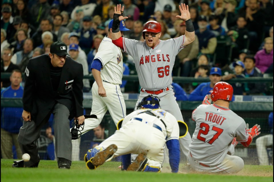 Los Angeles Angels' Mike Trout slides safely into home as Angels' Kole Calhoun (56) reacts to Seattle Mariners catcher Chris Iannetta bobbling the ball on the tag attempt in the eighth inning of Sunday's game in Seattle. Trout and Calhoun scored on a two-run single hit by Angels' Daniel Nava.