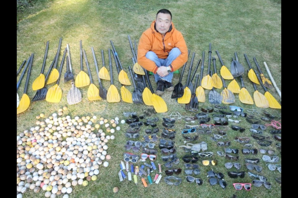 Henry Wang of Volunteers with Divers for Cleaner Lakes and Oceans sits with a collection of trash recovered from B.C.'s waters.