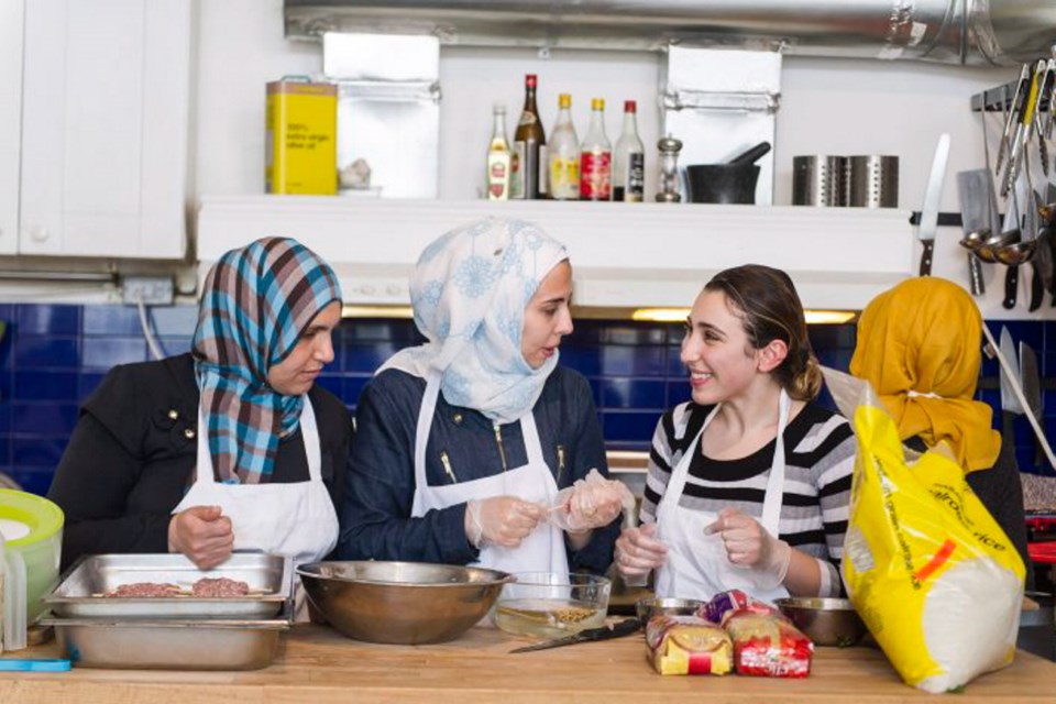 Syrian women prepare food at the Newcomer Kitchen Project at a restaurant in Toronto.