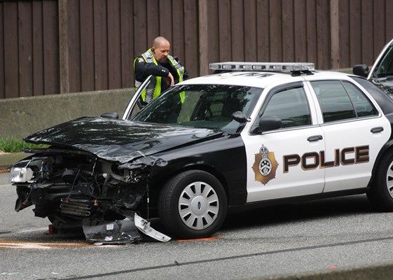 A West Vancouver police officer examines the damage to a department cruiser after an allegedly stolen SUV driving eastbound on Highway 1 near the Westmount overpass drove into it Tuesday afternoon.