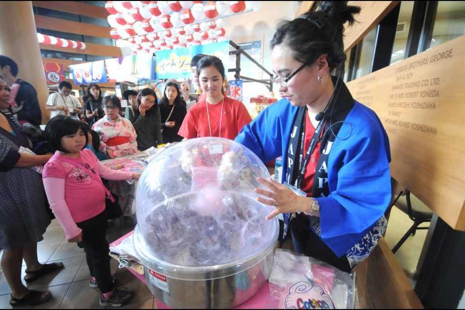 Karah Goshinmon (right) makes cotton candy with help from volunteer Maya Miller (centre in red).