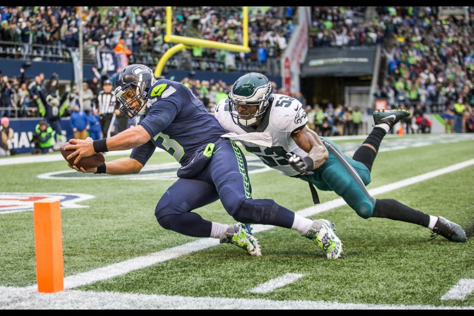 Seattle Seahawks quarterback Russell Wilson reaches for the end zone, scoring on a pass from wide receiver Doug Baldwin, past Philadelphia linebacker Nigel Bradham in the third quarter of Sunday's game in Seattle. Wilson became the first quarterback in franchise history to catch a touchdown, a perfect end-around pass from Baldwin to Seattle's athletic QB as he ran down the left sideline and dove into the end zone to give the Seahawks a 23-7 lead.