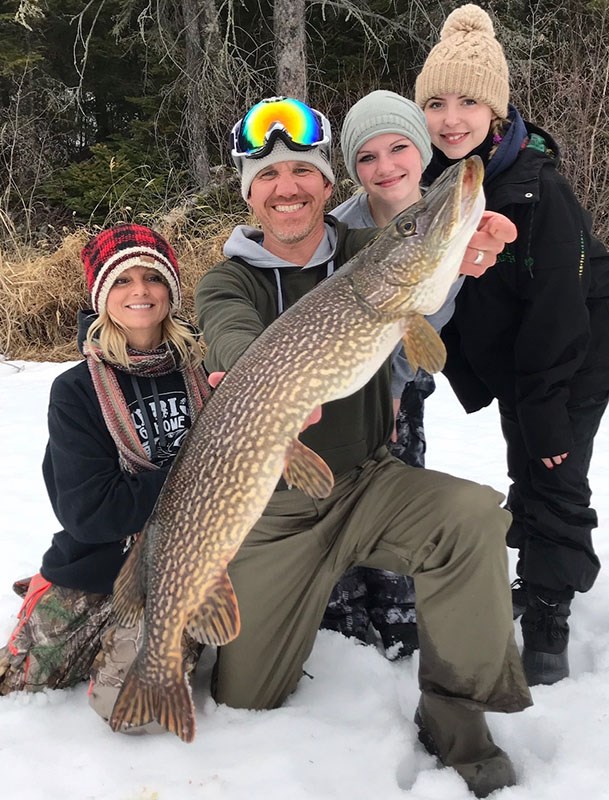 Happy customers haul in a hefty northern pike while ice fishing at Bakers Narrows Lodge near Flin Fl