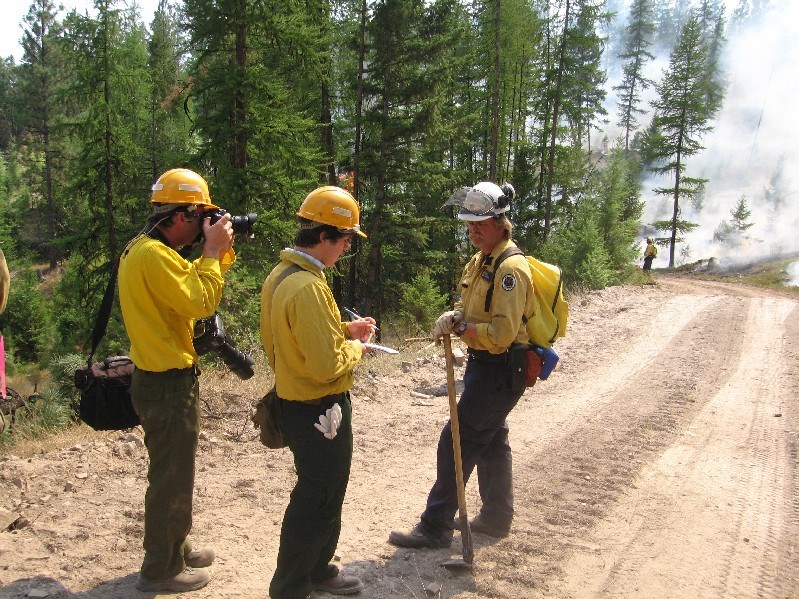 Manitoba #1 crew boss Keith Yarnell of the Marchand Fire Crew is interviewed by Kalipsell Daily Interlake reporter Nicholas Ledden as photographer Garrett Cheen tries to capture the moment on the line of the Chippy Creek fire Aug. 24, 2007.