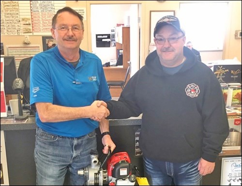 Delta Co-op Agro location manager Earl Hawthorne presents Alan Sopyc, Unity rural fire chief, with a Honda water pump. This pump enables a recently acquired ATV to dispense water from its tank to assist with fires in rural areas not accessible by the fire truck. Photo by Sherri Solomko