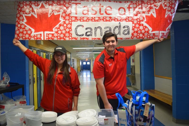 Seated under a large Taste of Canada banner, Laurissa Fedorchuk and Brayden Fatteicher welcomed everyone to the KCI gym for a sampling of typically Canadian foods.