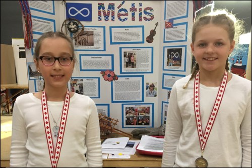 Niki Keramydas and Cassidy Alexander pose with their winning Heritage Fair project on Metis history.