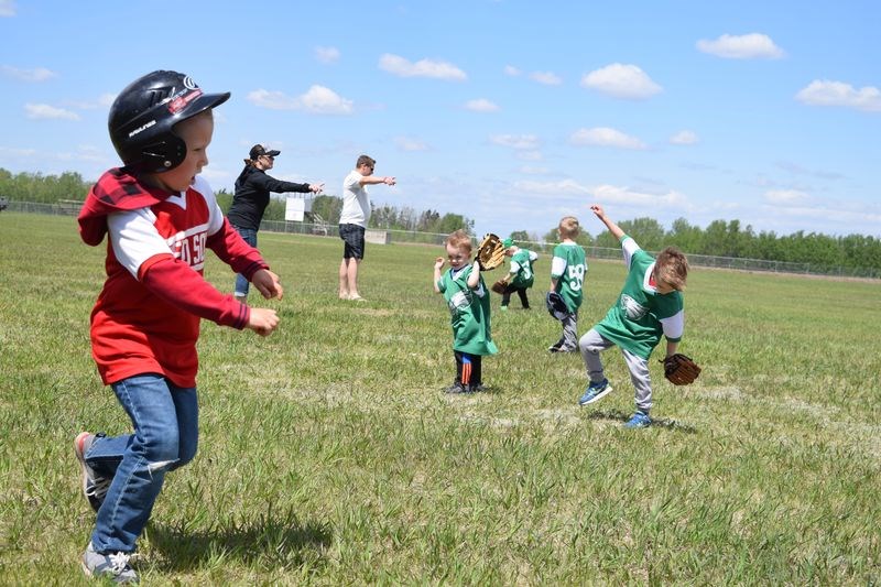 After a solid hit, Owen Van Brugge of the Canora T-ball team ran to first base during the game against Invermay on Canora Minor Ball Day. Coaches pointed to the ball, while Invermay fielders struggled against the whipping wind.