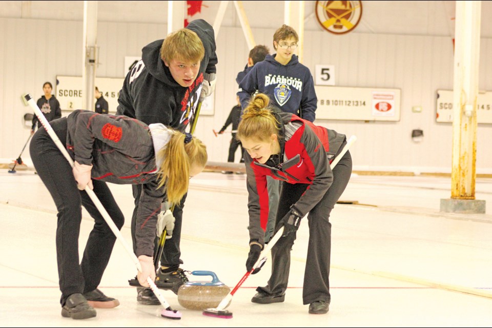 Hapnot curlers Kalena Kittle, Ryan Nawrocki and Hanna Baynton get sweeping during a match against the other Hapnot rink at the Zone 11 curling championships in Flin Flon on Feb. 3. - PHOTO BY CYNTHIA BIGRIGG