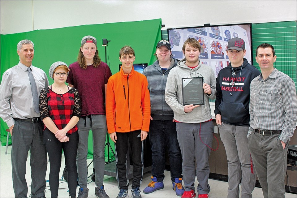 Hapnot Collegiate students and teachers pose with the Premier Award for School Board Innovation near the virtual reality (VR) system at the school. From left are principal Brent Bedford, Gracie Baynton, David Yarowy, Grady Bedford, Ethan VanKoughnett, Ryan Nawrocki, Michael Ward and teacher Daniel Dillon. - PHOTO BY ERIC WESTHAVER