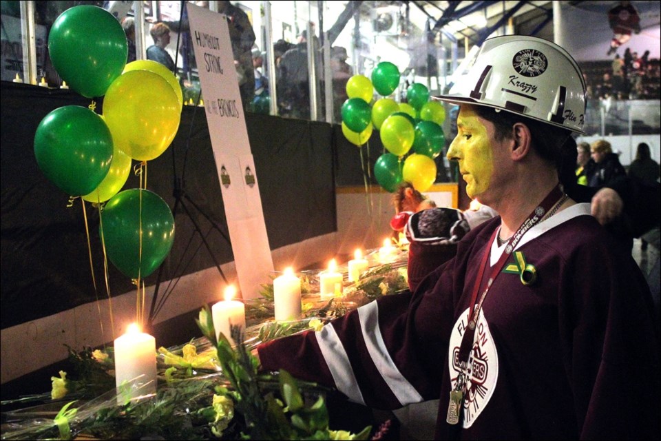 Flin Flon Bombers superfan Cory “Krazz” Krassilowsky lays down a flower at a memorial for victims of the April 6 bus crash. - PHOTO BY ERIC WESTHAVER