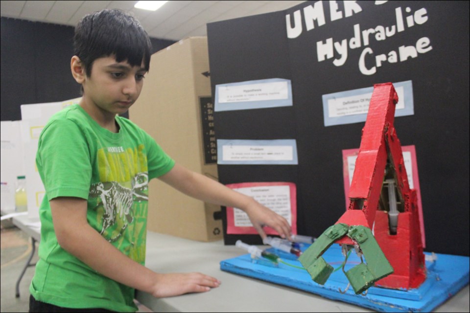 Grade 5 student Umer Lone shows off his homemade hydraulic crane during the Flin Flon City-wide Science Fair. Using a series of syringes and fluid-filled tubes, Lone’s crane was able to move up, down and laterally.	- PHOTO BY ERIC WESTHAVER