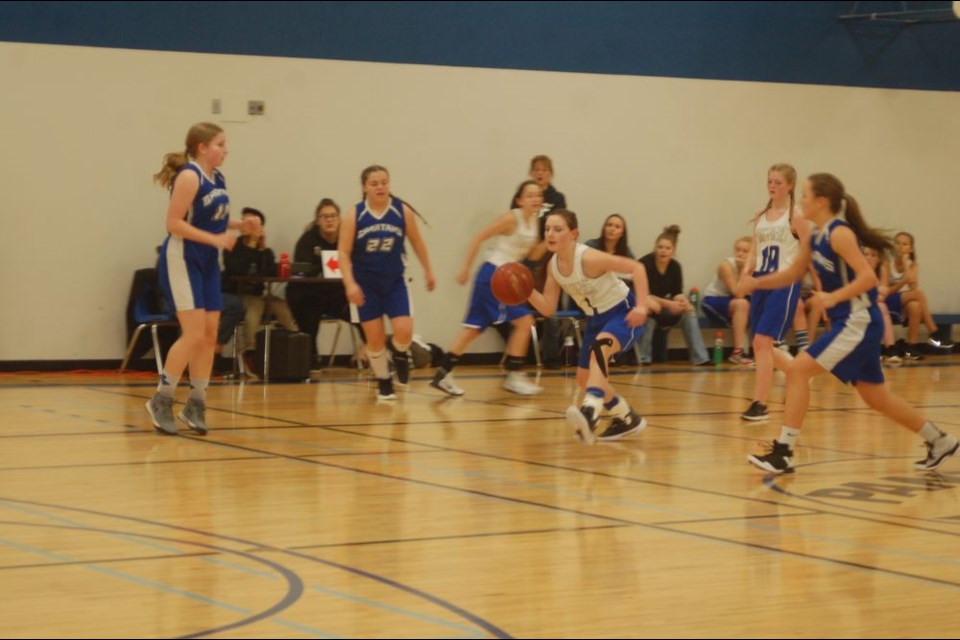 Shanae Shewchuk, left, and team-mate Kate Covlin (white jerseys) advanced the basketball towards the hoop.