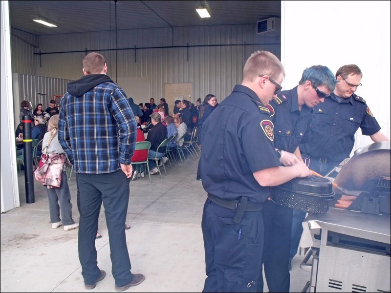 Firemen Conner, BJ and Jamie cooking burgers while patrons enjoy their supper at a barbecue April 10. Photos by Lorraine Olinyk