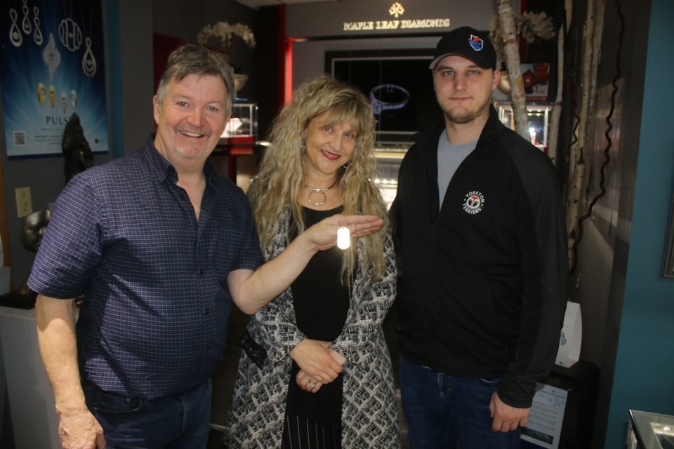 Bryce and Lorna Sherring, left and Terrier head coach Mat Hehr show off a dog tag created by Sherring Gold in the city.