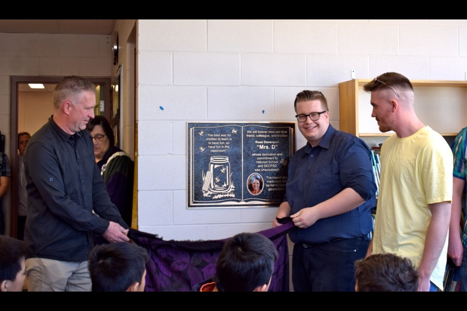 From left, Rose Davenport’s husband Shane and sons Cole and Carter unwrapping the plaque at the Rose Davenport Library at Hillcrest School. Photo by Anastasiia Bykhovskaia