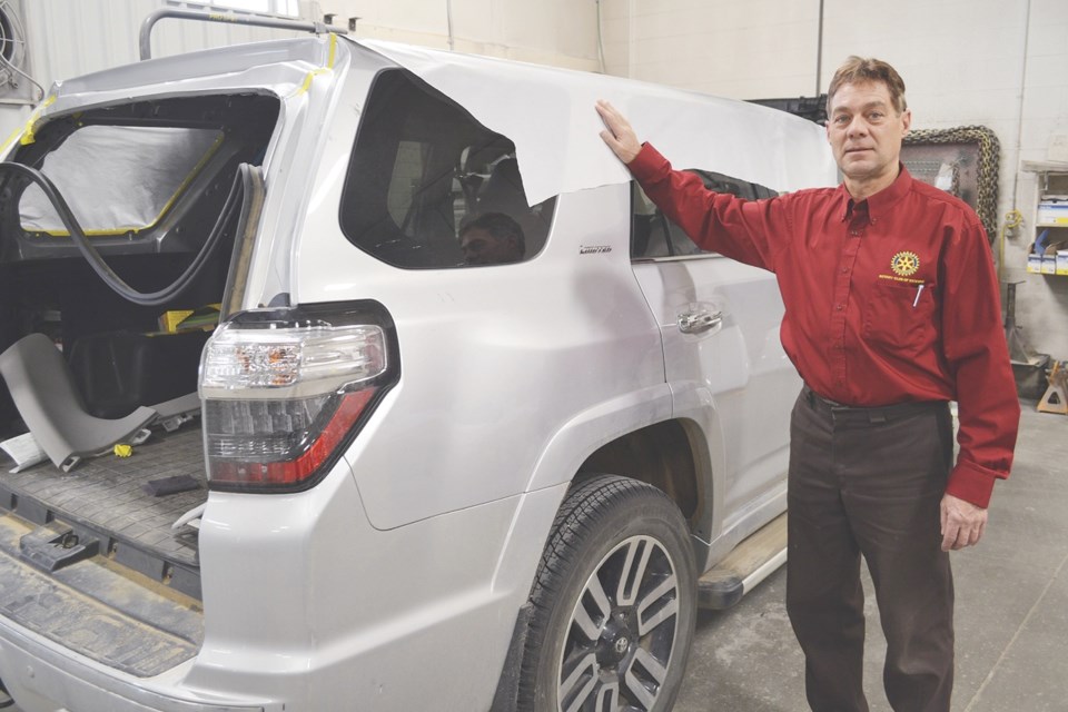 Bill Fonstad, owner of Ideal Autobody, stands next to one of the vehicles he has been repairing.