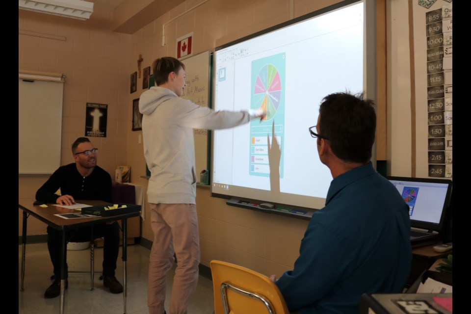 Sam Sheppard 'spins the wheel' which works on principles of probability as Aaron Keinle, left, and Quinn Haider watch for the result.