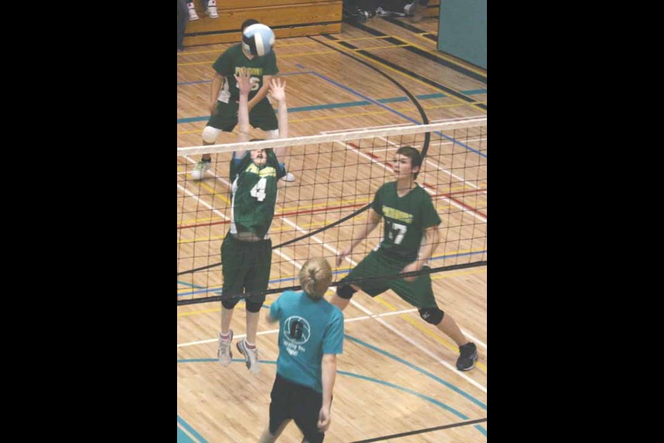 St. Paul's (in green) attackers go up for the spike at St. Michael's School gym.