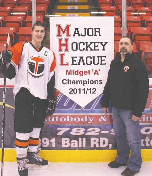 Mano's Restaurant Terriers' Elias Giannoulis and head coach Dwight Guy with the team's championship banner following the YMHA awards banquet last Tuesday night.