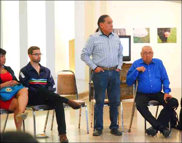 Wes Fineday (standing), storyteller, told those gathered at an artists' reception at the Chapel Gallery last week how the sacred circle is a place where people can connect to higher dimensions, to the spirit world
and healthy emotions, and become intellectually knowledgeable so they can lead their physical lives in a positive, sharing and healthy way. Elder George Benson (right) opened the reception with a prayer.