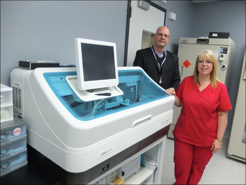 Paul Penner of Diagnostic Services of Manitoba and Christine Whitbread, charge technologist at the lab, stand in front of a new diagnostic unit known as the Cobas E411.