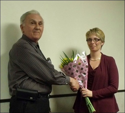 Larry Trischuk presenting a bouquet of flowers to Val Fendelet, RM of Great Bend administrator.