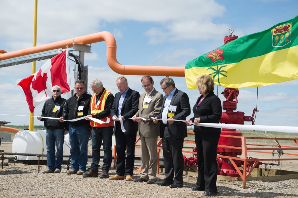 Dozens attended the ribbon cutting ceremony for the Aquistore research site. The injection well is behind the dignitaries. Cutting the ribbon are, from left, Dennis Moore, Estevan city councillor; Kelly Lafrentz, reeve of the RM of Estevan; Grant Ring, vice-president of business development at SaskPower; Ken From, PTRC CEO; Herb Cox, minister of Environment; Ed Komarnicki, MP; Doreen Eagles, Estevan MLA.